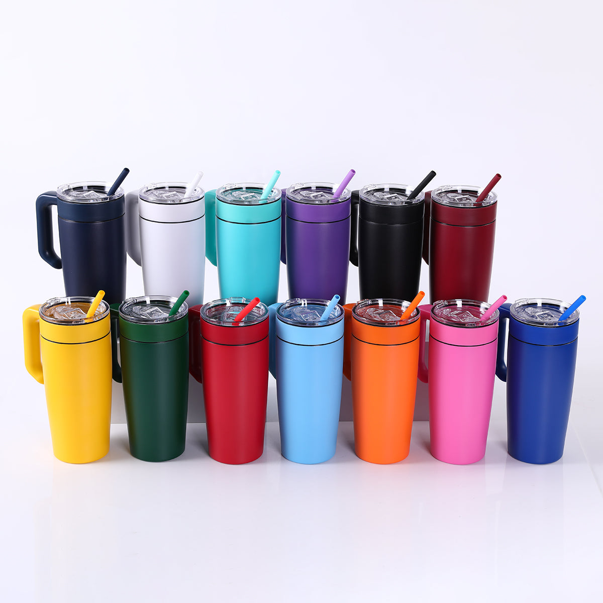 Assorted colorful 20oz tumblers with handle and straws on a white background